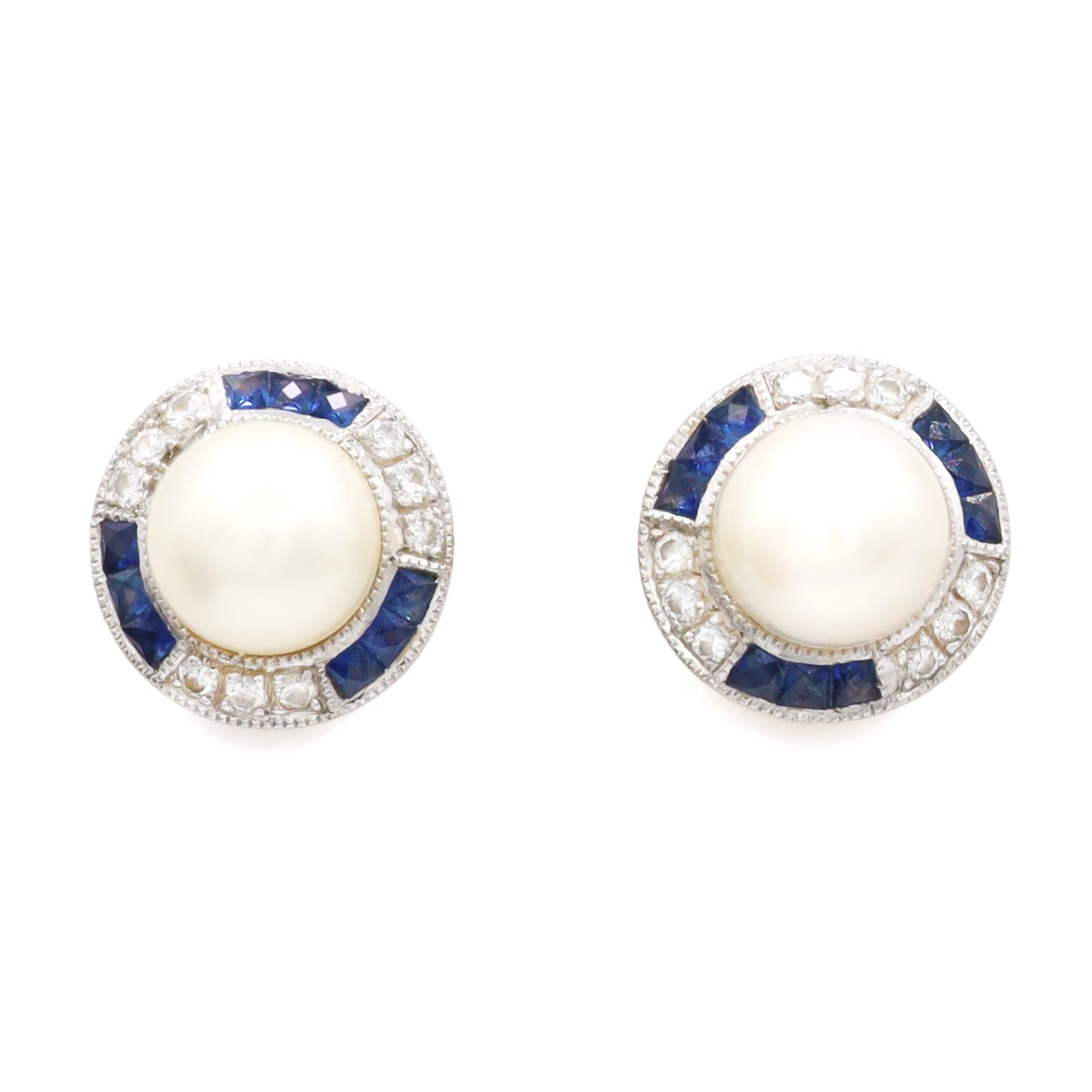 Pair of pearl, sapphire and diamond milgrain set earrings, each stud set with a cultured white pearl, surrounded by alternate calibre cut sapphires and round brilliant cut diamonds, London import mark 1994