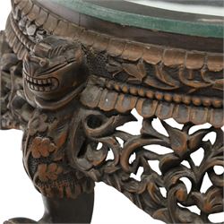 19th century Burmese carved hardwood jardinière stand, circular glazed top over pierced and carved floral frieze, on four zoomorphic supports carved with mythical beast masks and paw feet