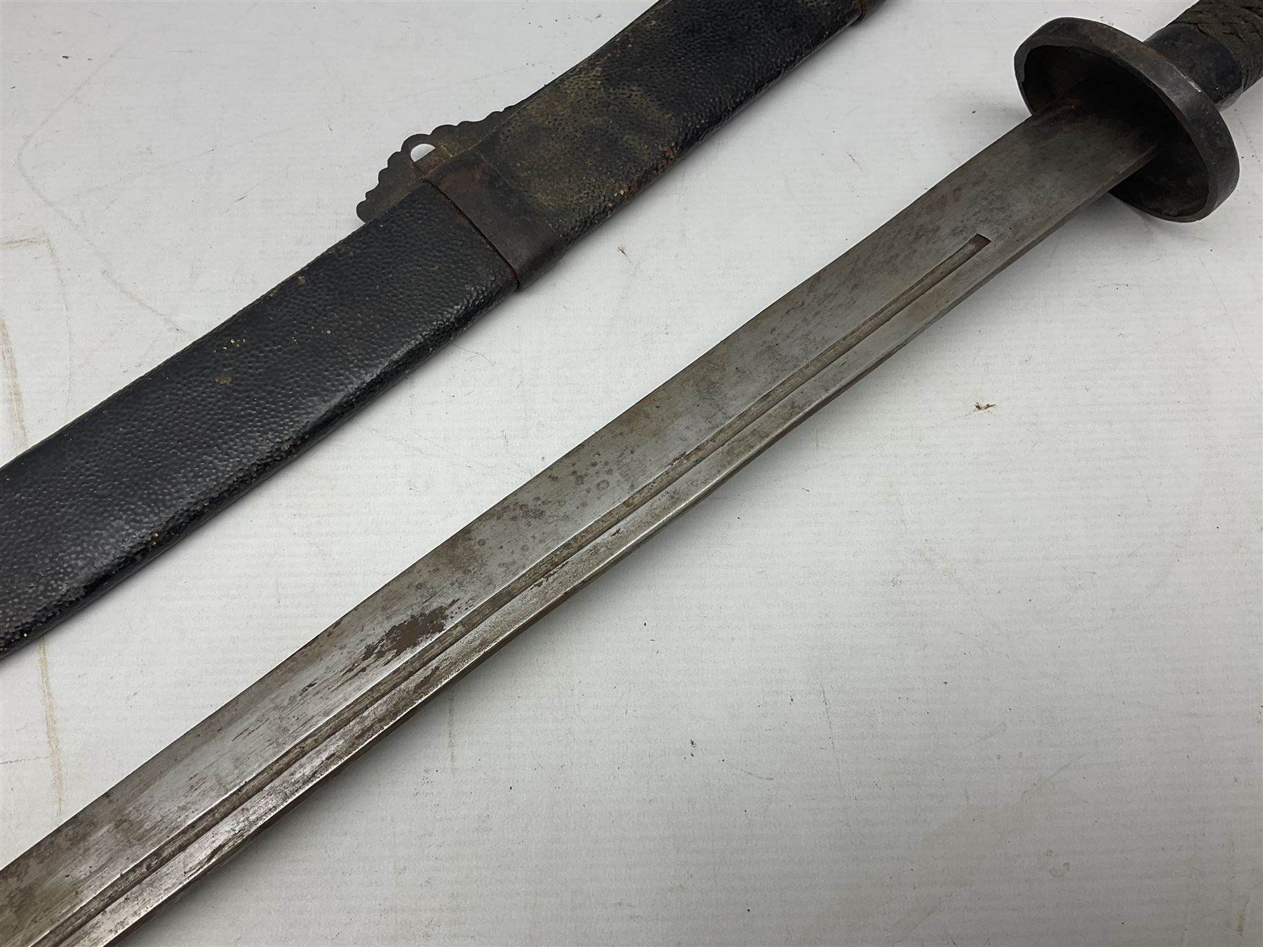 Chinese Boxer Rebellion Period Sword, 69.5cm heavy curved single edge blade with single narrow fuller, plain iron dished circular guard, iron pommel and ferrule with plaited cord bound grip; in skin covered wooden scabbard with iron chape and long suspension mount L95cm overall