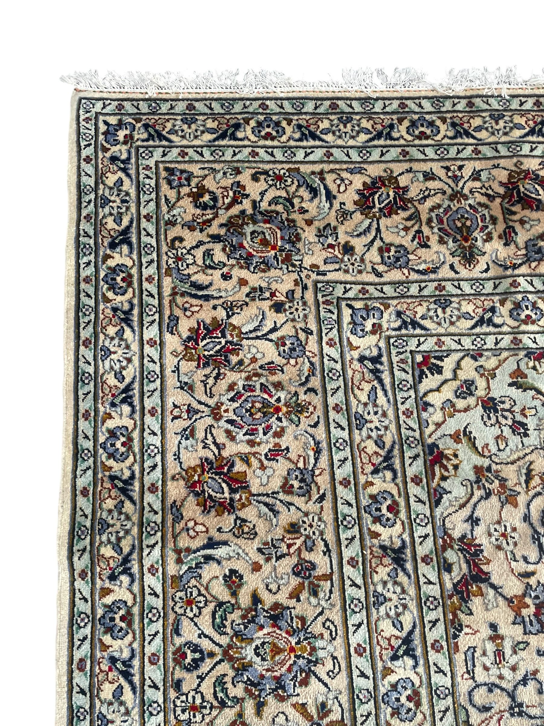 Persian Kashan ivory ground carpet, the field decorated with interlacing foliate branches and stylised plant motifs, scrolling border decorated with repeating palmettes, within floral pattern guard bands