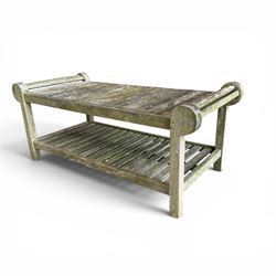 Lutyens design weathered teak garden bench with matching two-tier table, the bench with shaped arched and slatted back over rolled arms and slatted seat