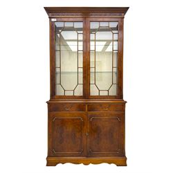Ian Smith Furniture - Georgian design walnut bookcase on cupboard, projecting cornice above a pierced geometric frieze, featuring two astragal-glazed doors enclosing two adjustable shelves, the base with two drawers above a double cupboard, on a shaped plinth base