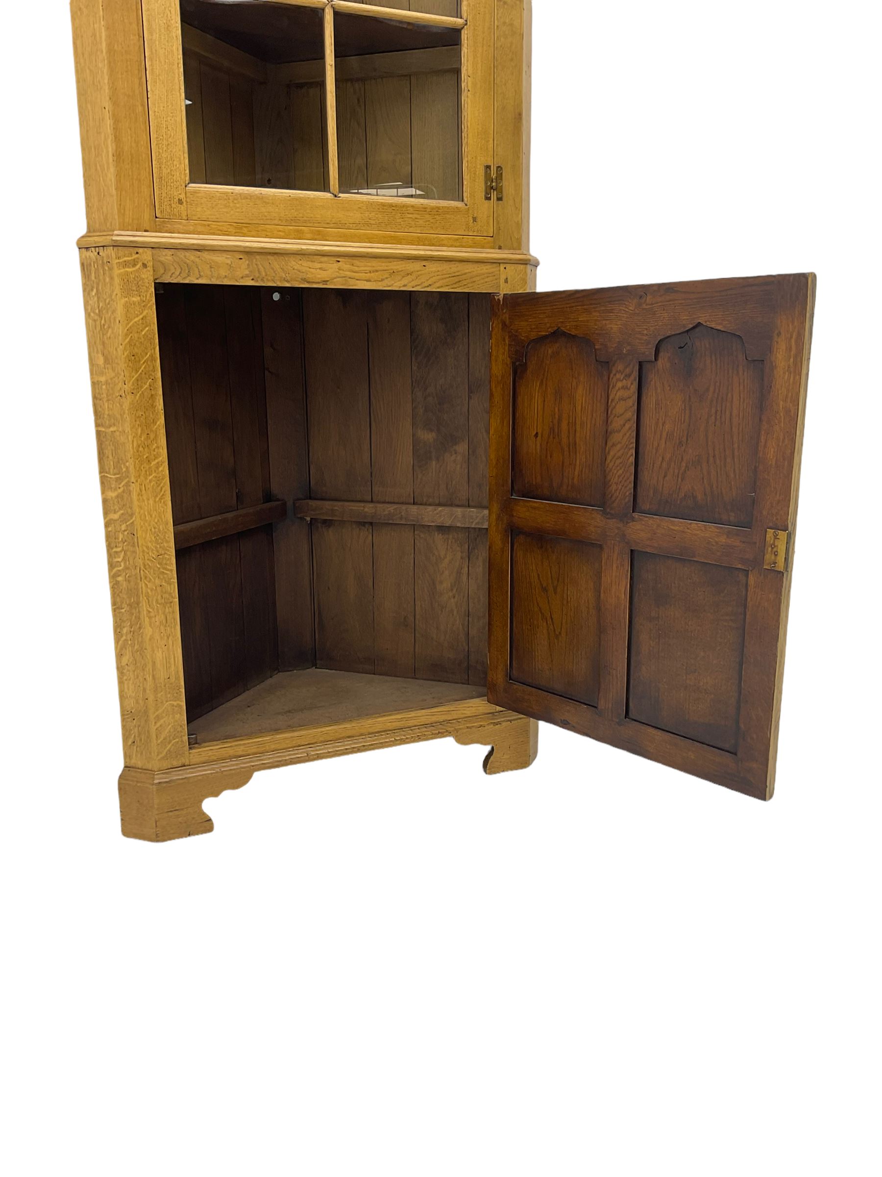 Traditional light oak corner cabinet, projecting cornice, dentil frieze, single glazed door above single fielded door