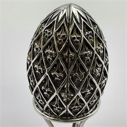 Modern silver limited edition Easter egg, no. 70/500, the openwork lattice body decorated with gilded panels of flower heads, opening to reveal a gilt interior, upon silver stand with three scrolling pad feet, each hallmarked St James House Company, London 1979, height including stand 8cm