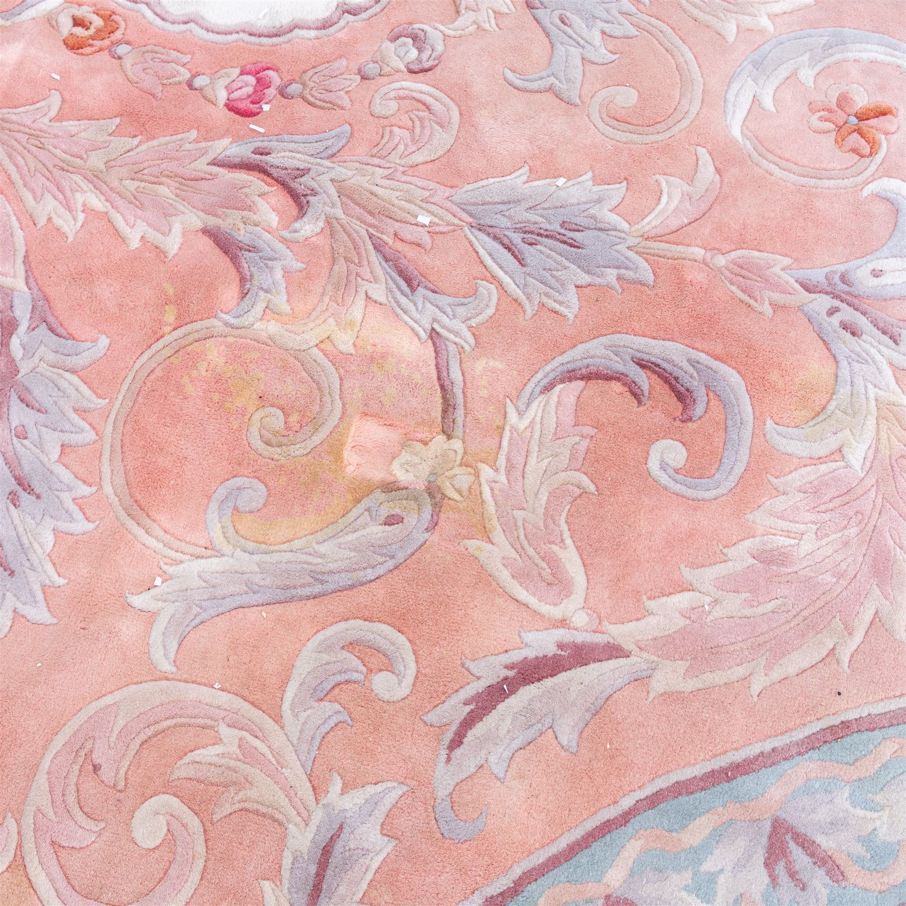 Large late 20th century Aubusson style wool carpet, peach and pastel toned field with central floral medallion enclosing scrolling acanthus and and foliate sprays, surrounding field decorated with further stylized foliage and and floral ornament, within shaped reserves and indigo corner spandrels, enclosed by narrow guard border, cotton fringe ends