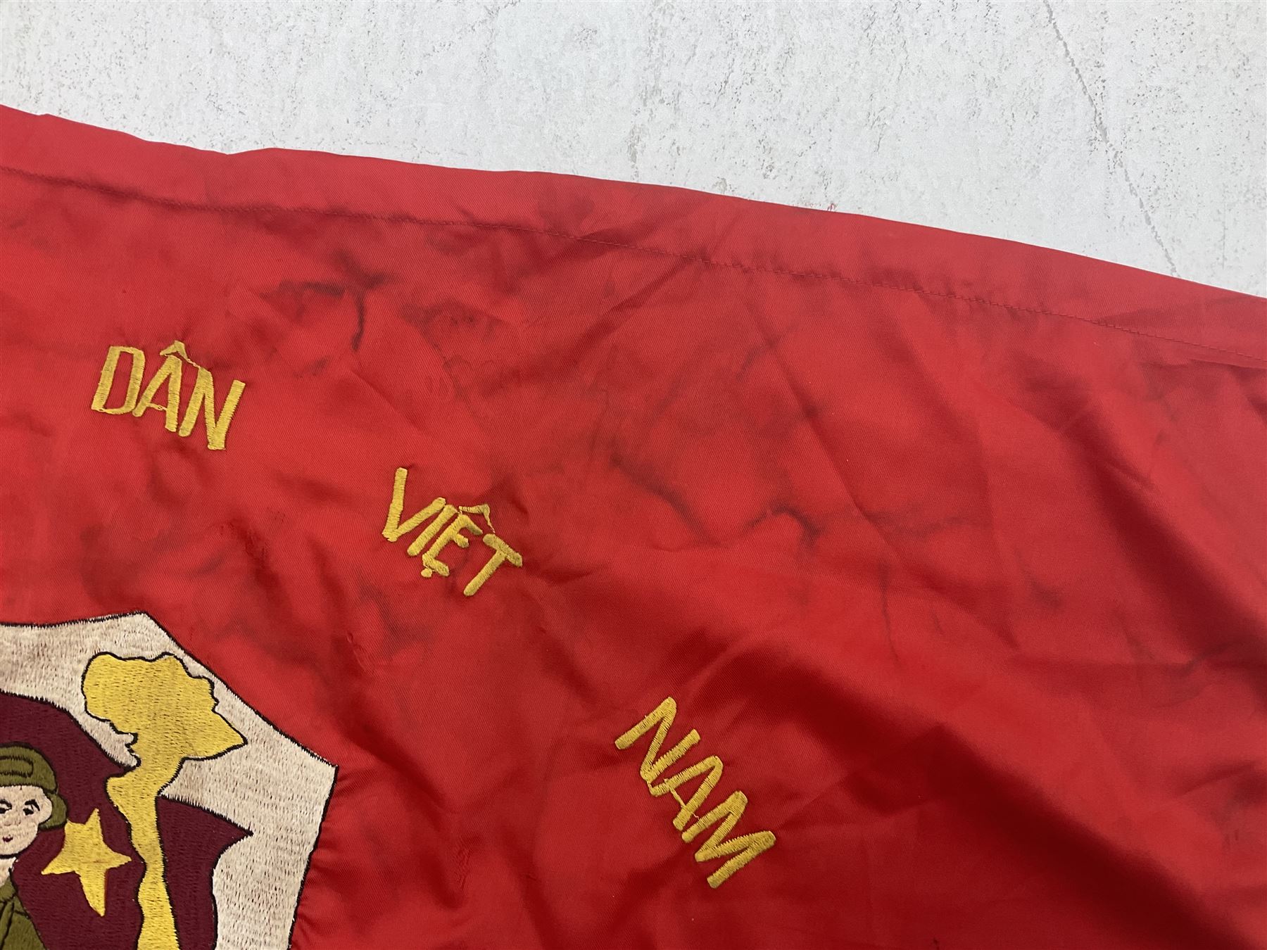 1960s North Vietnam banner embroidered in yellow thread on a red ground, roughly translates as 'Peoples Army of Viet Nam. Warriors of Viet Nam Determined To Keep The Country 1964' around a central military crest with the motto 'Warriors Keep The Country'; tassels to three sides 70 x 100cm