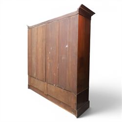 Edwardian inlaid mahogany triple wardrobe, featuring two oval mirror doors with bevelled plates, enclosing central figured veneered panel with mouled detail, above three base drawers