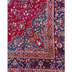 Pair of Persian wool rugs, each with rich red ground, one centred with a diamond-shaped medallion and navy spandrels within a floral field, the other with radiating floral medallion and scrolling foliate motifs, both enclosed by multiple borders with palmette and flowerhead designs, from the region of Kashan 291x376, 299 x 378 