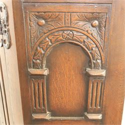 20th century dark stained oak hall robe, cantered sides enclosing a hooks and a shelf, panelled and carved sides, raised on stile supports