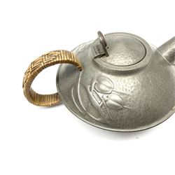 Archibald Knox for Liberty & Co Tudric pewter three piece tea service, comprising teapot with woven reed handle, single handled open sucrier, and milk jug, each with planished finish and detailed with honesty flowers, each impressed beneath Made in England Tudri Pewter 0231 