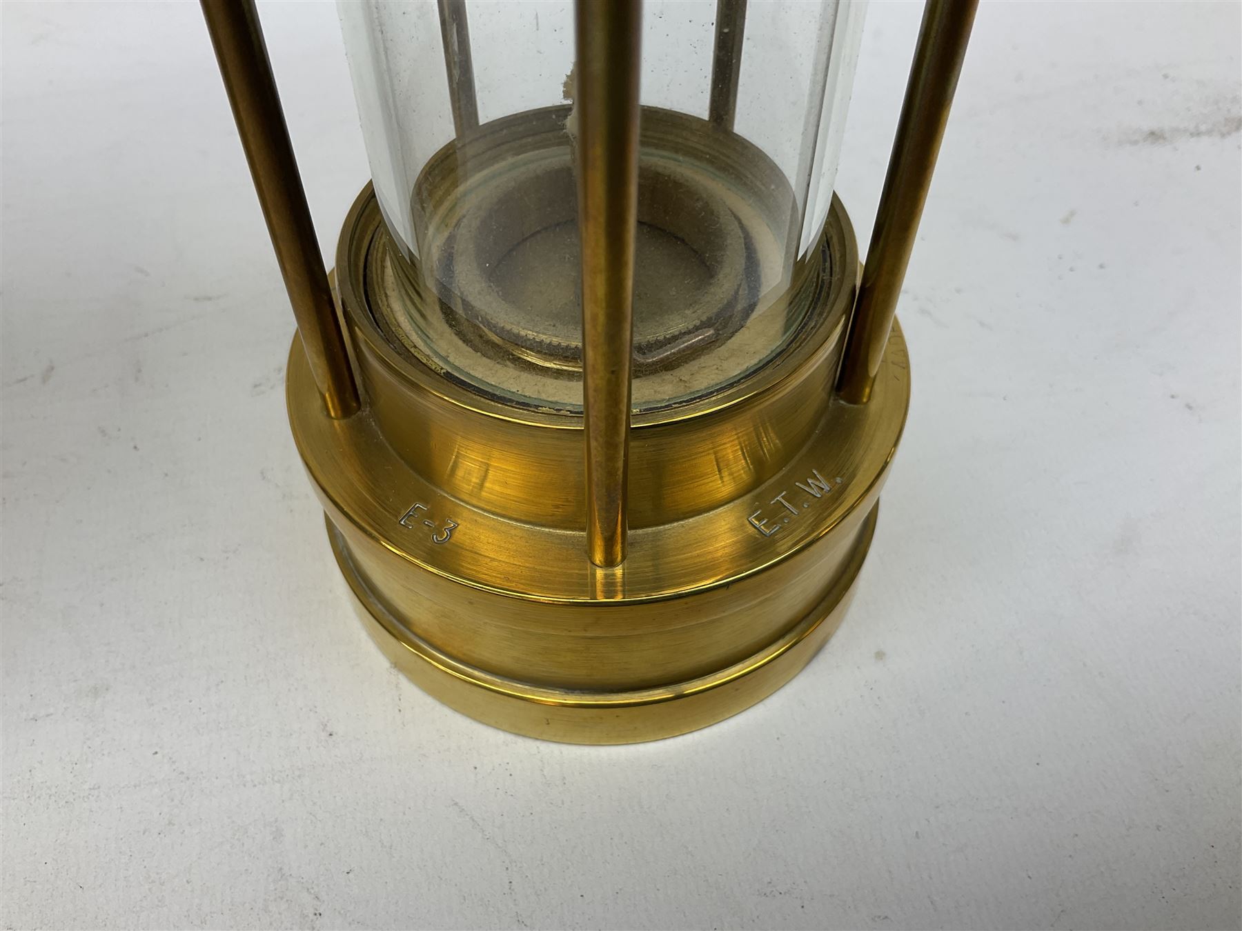Four miners lamps, comprising Clanny miners lamp, with flip top and gauze protected by three rods, stamped E.T.W E-3, lamp with a gauze chamber protected by three rods, and two E. Thomas & Williams Ltd lamps, tallest example H26cm