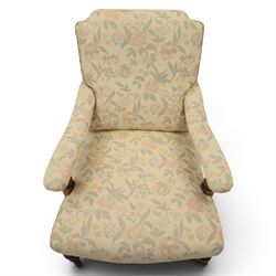 Victorian mahogany framed deep seat low drawing room chair, upholstered in beige floral fabric, on turned supports terminating in castors