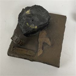 Bronzed cold cast figure of a miner sat beside a lamp by Robert Olley on rocky square plinth base, H17cm