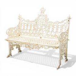 Victorian revival heavy cast iron garden bench, ornate back rest with scrolls, floral motifs and central crest, pierced lattice seat, curved arms and decorative legs, painted in antique white, in the Gothic Coalbrookdale style