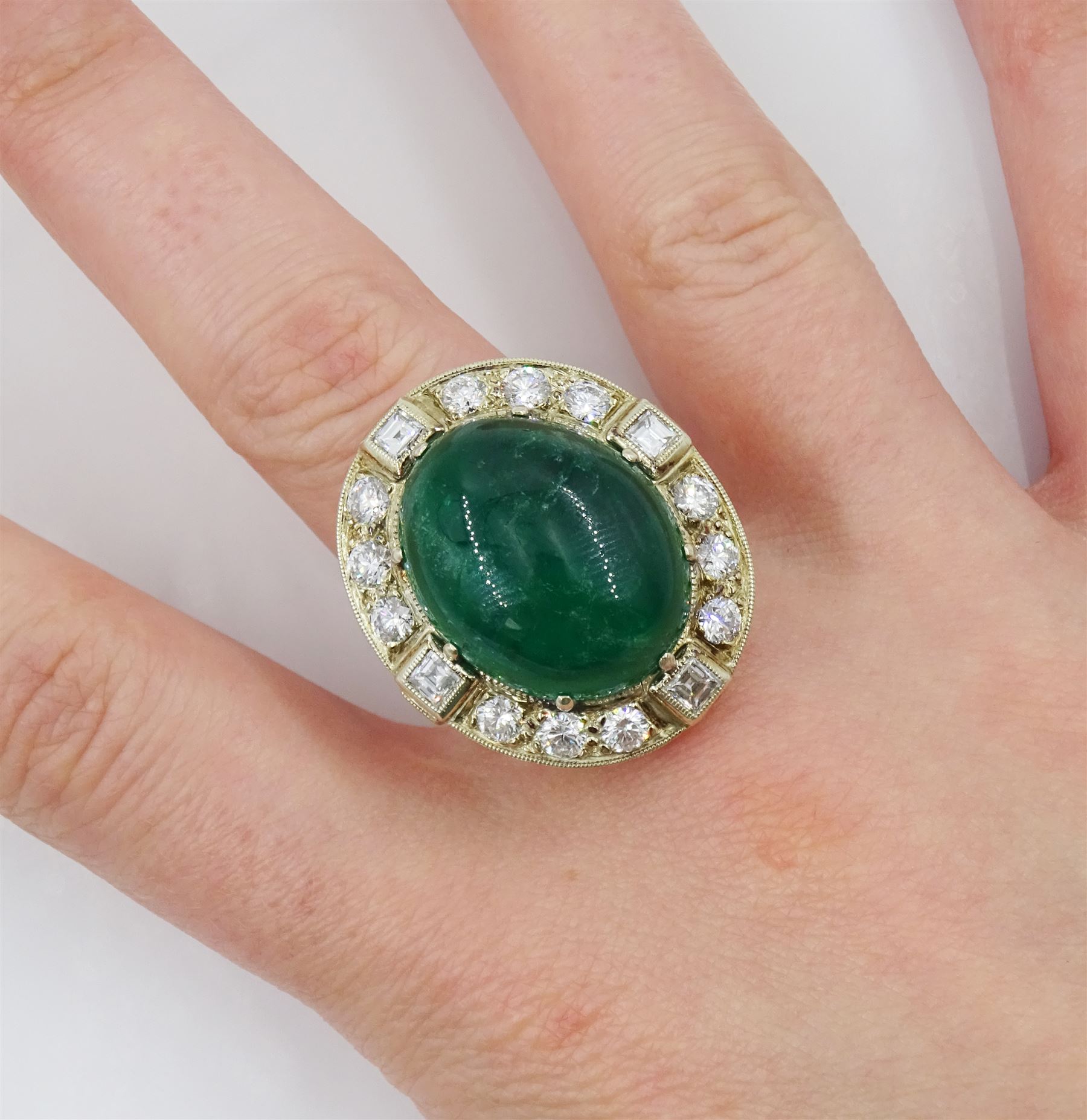 Gold emerald and diamond ring, the central oval cabochon emerald, with sixteen round and rectangular cut diamond halo surround by Judith Crowe, hallmarked 9ct, emerald 20.00 carat, total diamond weight 2.00 carat, with World Gemological Institute report
