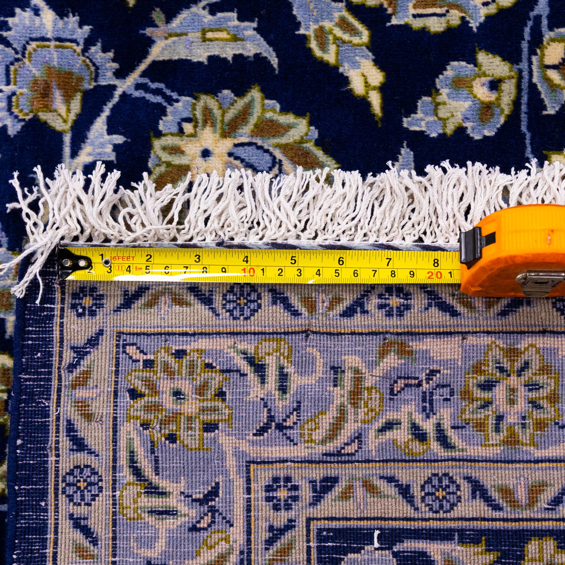 Central Persian Kashan hand-knotted carpet, deep indigo blue field densely decorated with all-over vine, palmette and flowering sprays arranged in a symmetrical pattern enclosed by broad navy border of stylized palmettes, and foliate vine decoration between multiple guard stripes, with cotton fringe ends 