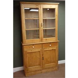  Traditional solid pine display bookcase on cupboard, two glazed doors enclosing shelves above two drawers and two cupboard doors, plinth base, W111cm, H209cm, D43cm  