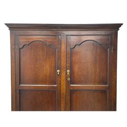 George III oak livery cupboard, projecting moulded cornice over two panelled doors, the upper panels within stepped ogee and arched moulded frame, the interior fitted with a single row of wooden hooks, two short and one long drawers, on bracket and return skirted base 