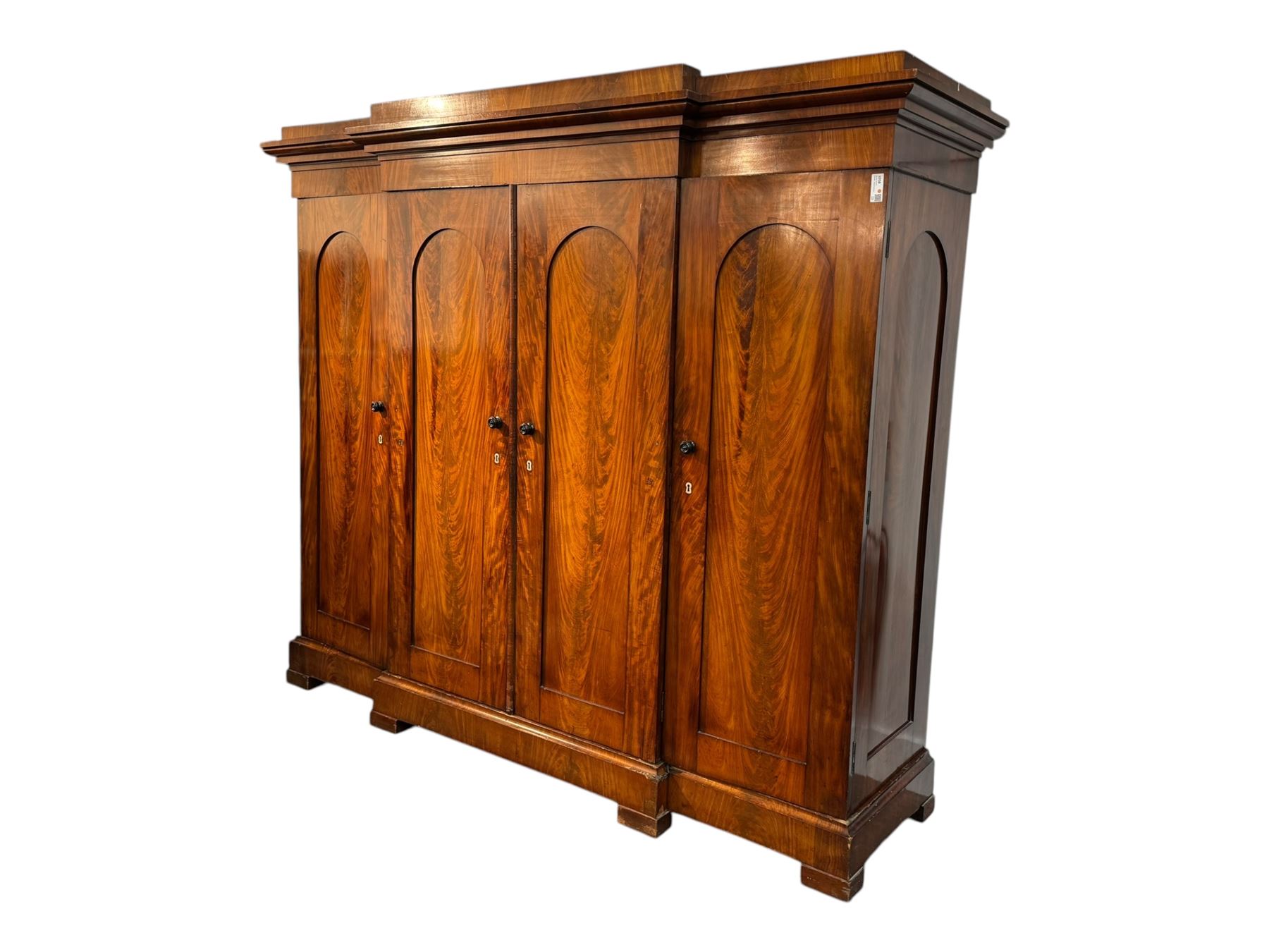 19th century mahogany break-fronted quadruple wardrobe, stepped and moulded projecting cornice over four arch panelled doors, moulded plinth base on blocks 