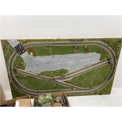 '00' gauge model railway layout of oblong form on six removable tubular legs, the outer loop enclosing further track amongst simulated grass and mossy vegetation, box of removed buildings and accessories and large quantity of additional track included 183 x 108cm