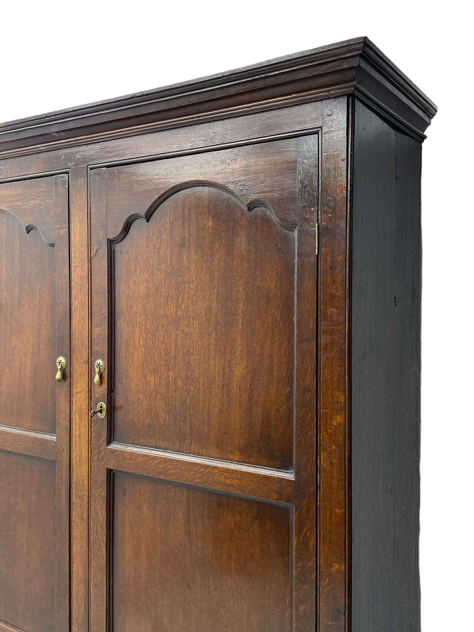 George III oak livery cupboard, projecting moulded cornice over two panelled doors, the upper panels within stepped ogee and arched moulded frame, the interior fitted with a single row of wooden hooks, two short and one long drawers, on bracket and return skirted base 