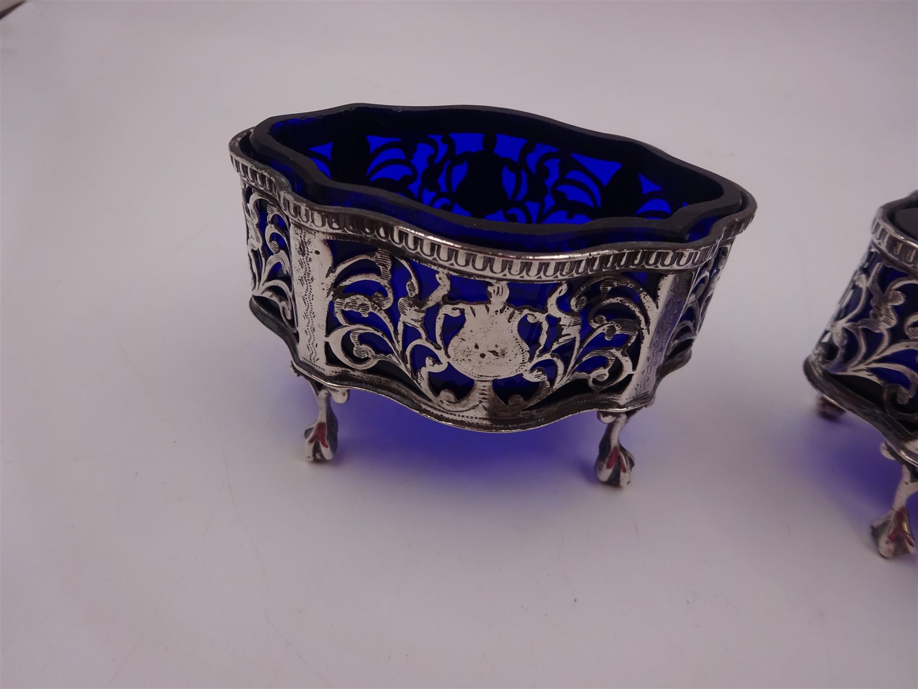 Pair of Victorian open silver salts with pierced sides, upon four ball and claw feet, hallmarked George Nathan & Ridley Hayes, Chester 1900, H5.2cm, each with blue glass liner