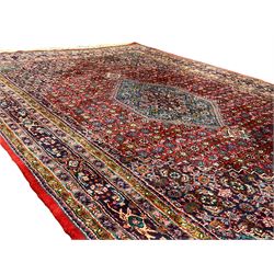 Persian crimson ground rug, central hexagonal medallion surrounded by all-over stylised plant and bird motifs with contrasting spandrels, multi-band border with repeating palmettes 