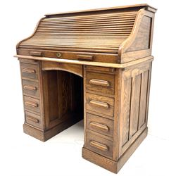 Early 20th century oak twin pedestal shaped tambour roll top desk enclosing fitted interior, two slides, seven graduating 