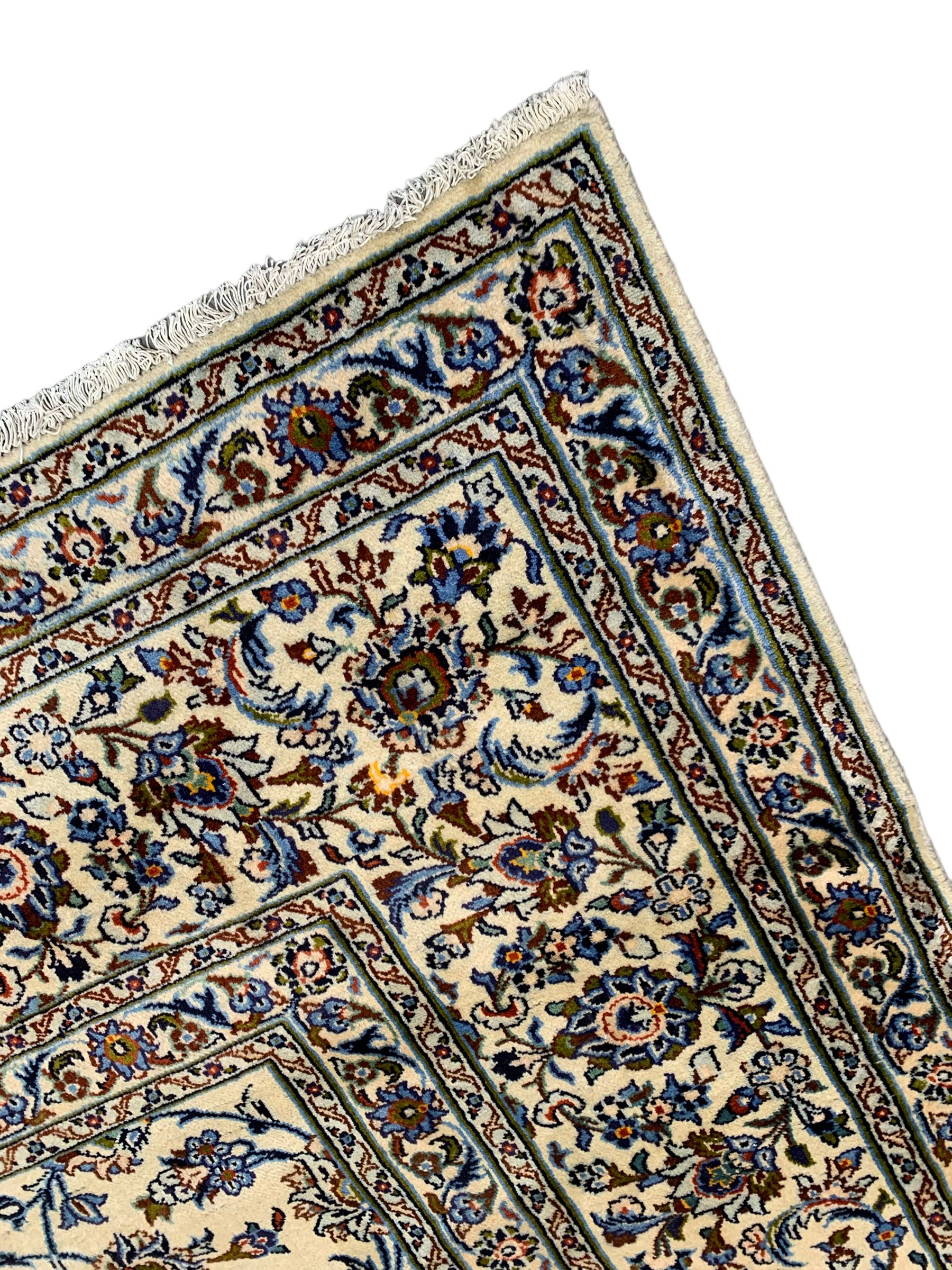 Persian Kashan ivory ground carpet, the field decorated with interlacing leafy branches and stylised plant motifs, repeating border with multiple guards