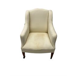 Edwardian wingback armchair, upholstered in white frame cover with sprung back and seat, raised on square tapering supports with castors