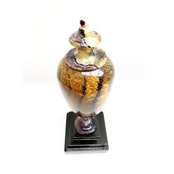 Early 19th century and later Blue John urn, Winnats one vein, of ovoid form with integrated cover and ball finial, upon a spreading circular base, and square stepped black lacquered base, H34.5cm