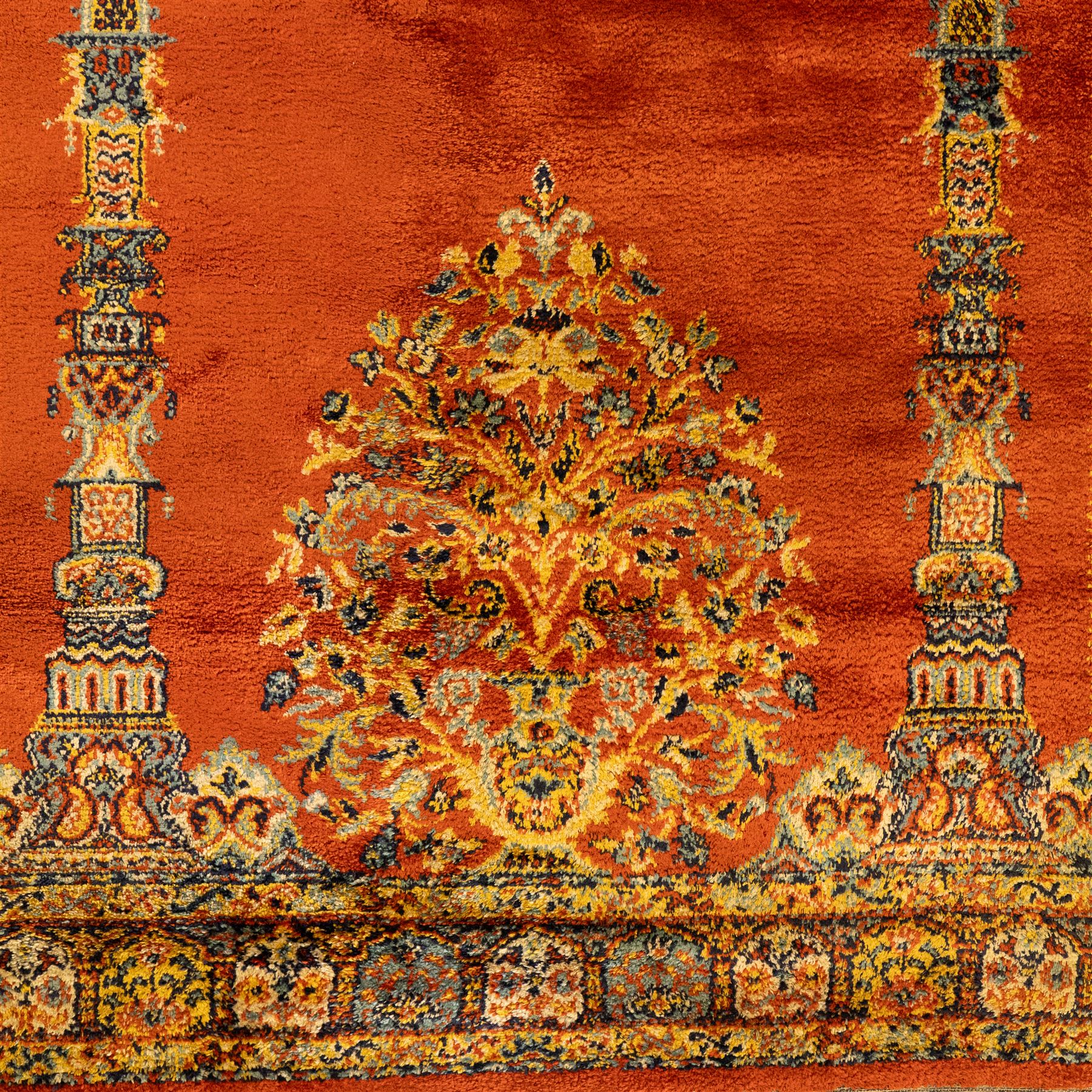 Persian Kashan prayer rug, rust red field with mihrab arch design, suspended floral hanging lamps, and a central flowering vase framed by columnar supports enclosed by palmette and meandering vine border