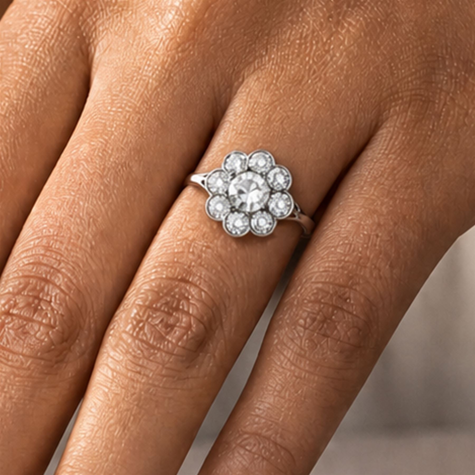 Early 20th century platinum diamond daisy flower head cluster ring, principal round cut diamond of approx 0.65 carat, surrounded by eight milgrain set old cut diamonds, within a pierced scroll design gallery, total diamond weight approx 2.15 carat