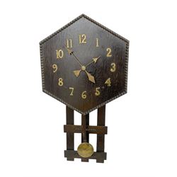 1920’s Art deco drop dial wall clock - with an eight day spring driven timepiece movement, hexagon dial in dark oak with applied brass Arabic numerals and arrow shaped hands, open framework backboard, visible wooden pendulum with a brass faced bob.