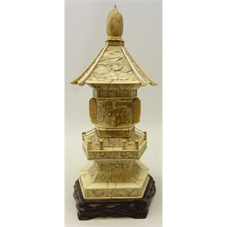  Early 20th century Chinese carved ivory Pagoda, the hexagonal sloping rood carved with a cockerel amongst lily pads, with two hinged doors opening to reveal a seated god, above two tiers carved with figures and dragons, on carved hardwood base, H40cm   