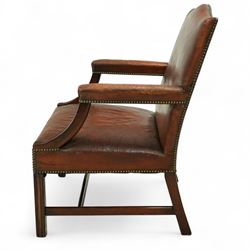 Early 20th-century Gainsborough-style library armchair, padded back, arms, and seat, brass button upholstered in brown leather, on square tapered front legs united by a stretcher 