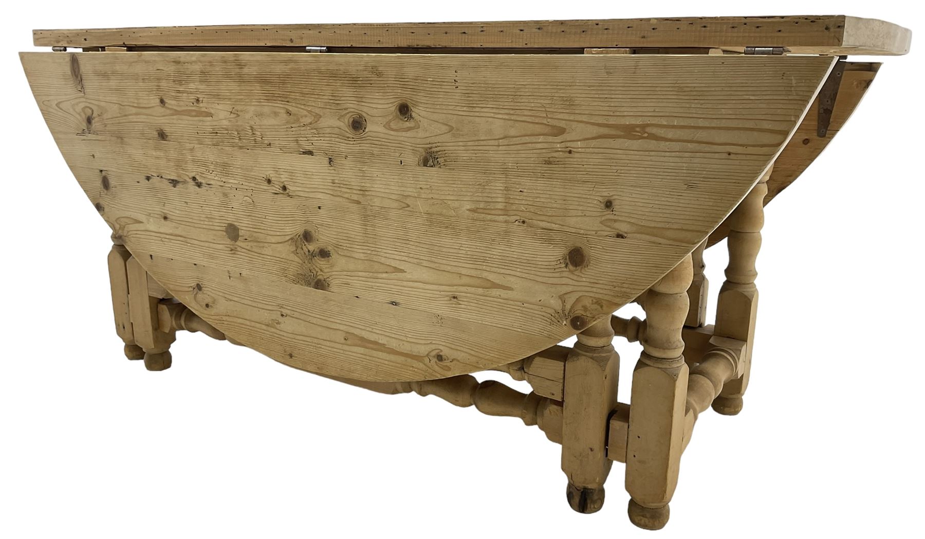 Traditional stripped pine dining table, circular drop-leaf top over double gate-leg action base with turned supports united by turned stretchers