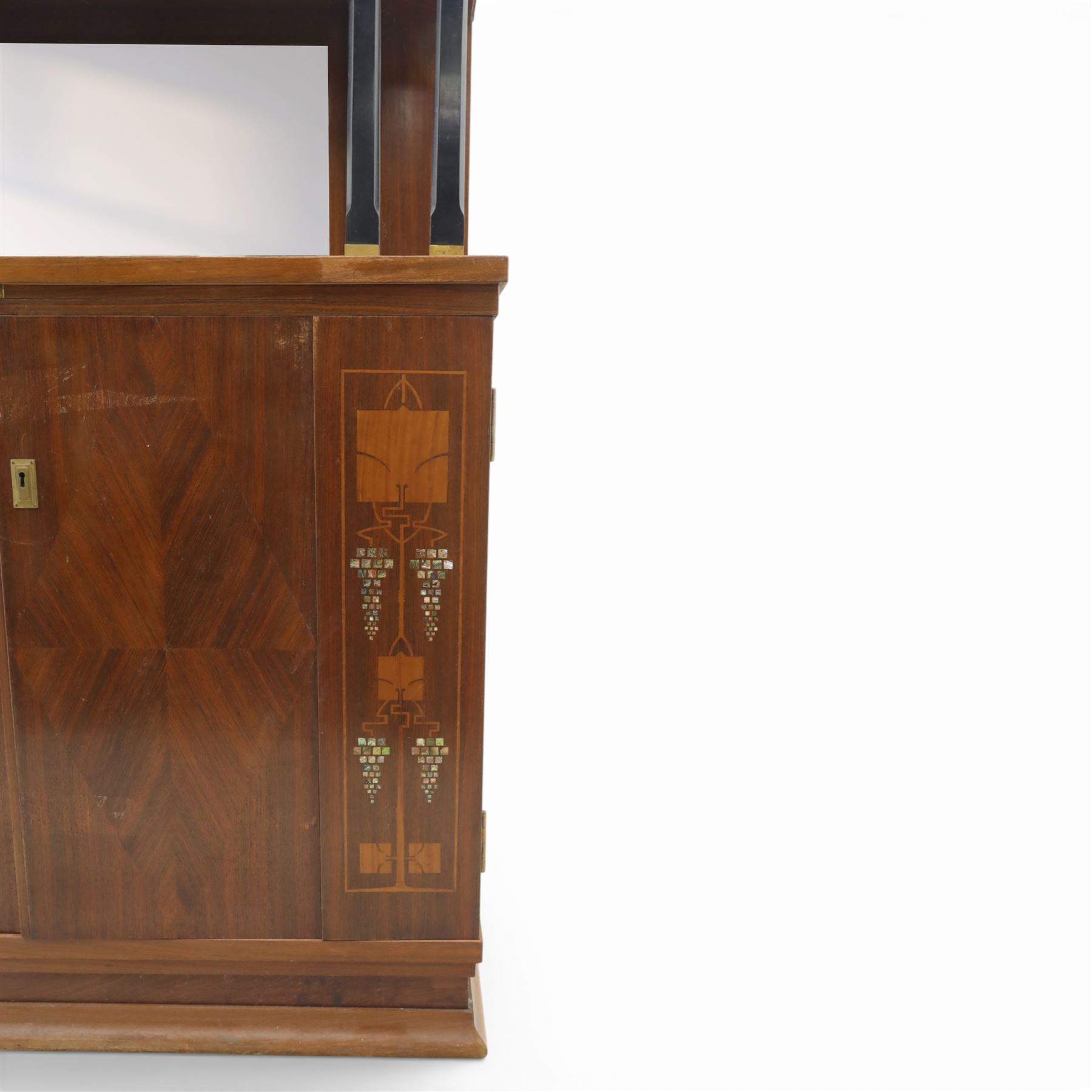 Continental Art Nouveau cocktail cabinet, the stepped cornice over a glazed upper section with panelled doors, enclosing fitted shelf, the central section with mirrored back and green baize serving surface flanked by ebonised and gilt detailed pilasters, the base fitted with cupboard doors inlaid with stylised foliate and geometric motifs, on a plinth base