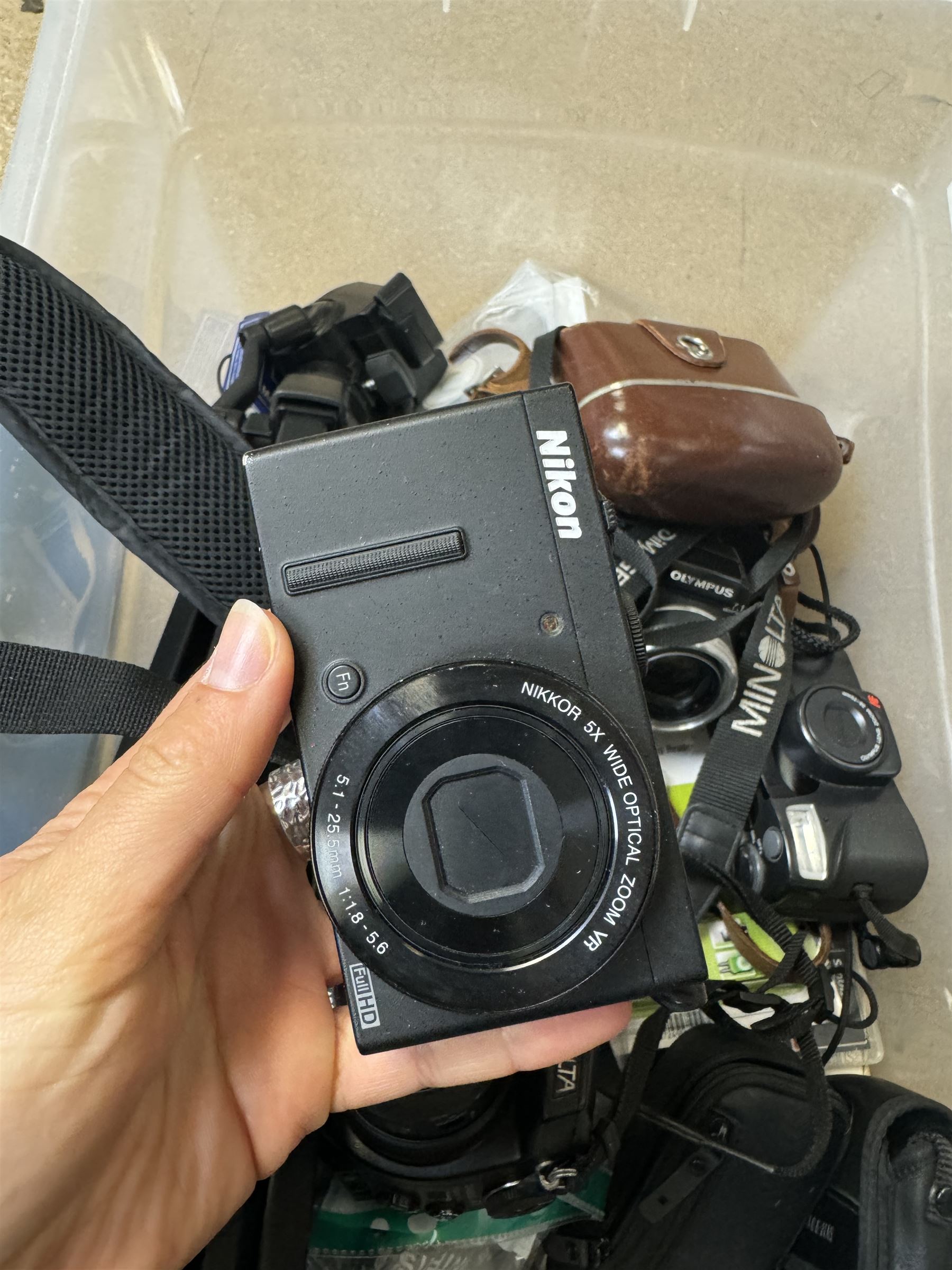 Collection of cameras and camera equipment, including Voigtlander Vitomatic I, Nikon Coolpix P340, Nikon Coolpix S9100, Olympus SP-510UZ, tripod, cases, etc