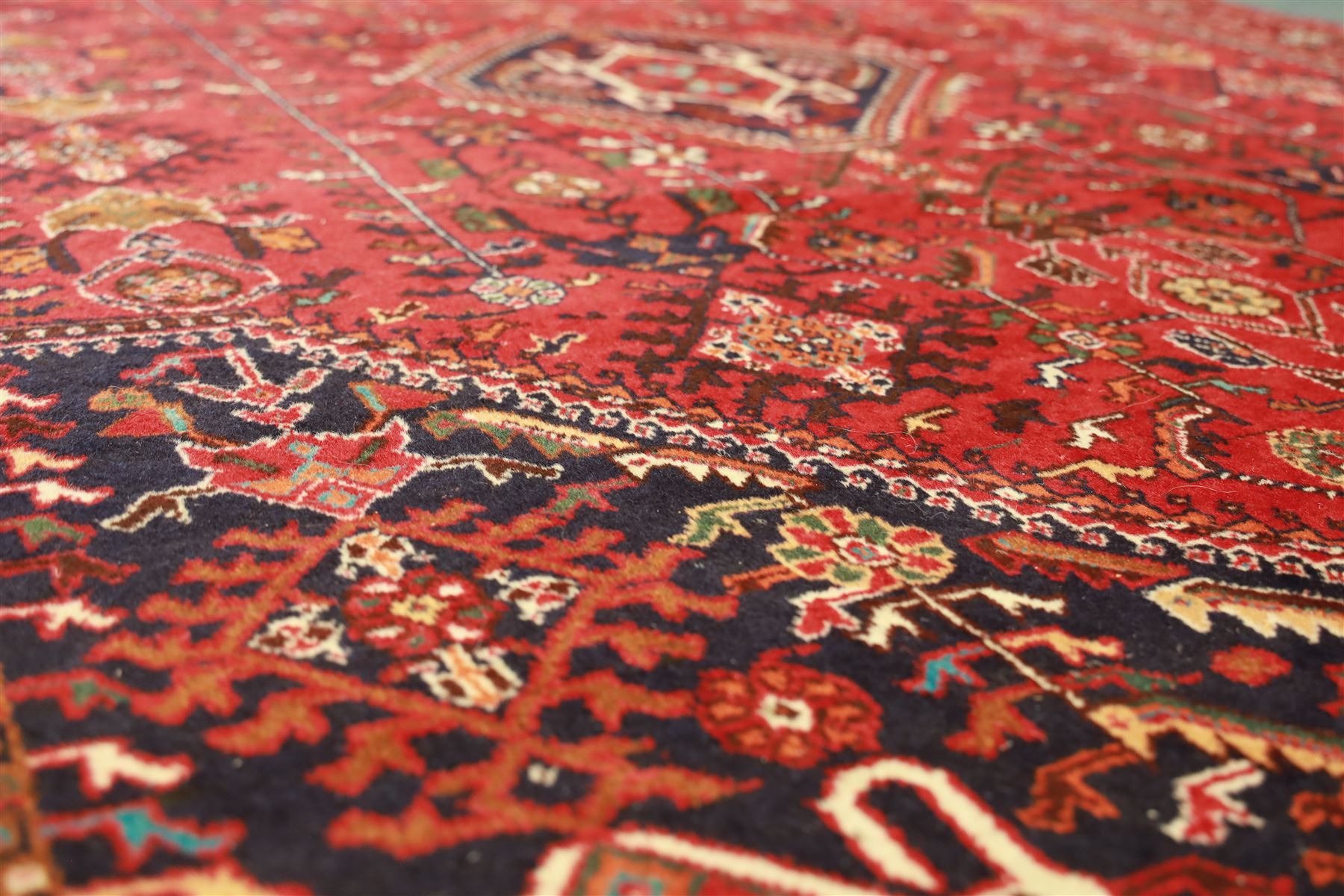 Persian tribal hand-knotted rug, crimson ground, madder field with central stepped lozenge medallion with scattered floral and geometric spandrels with rosette border 