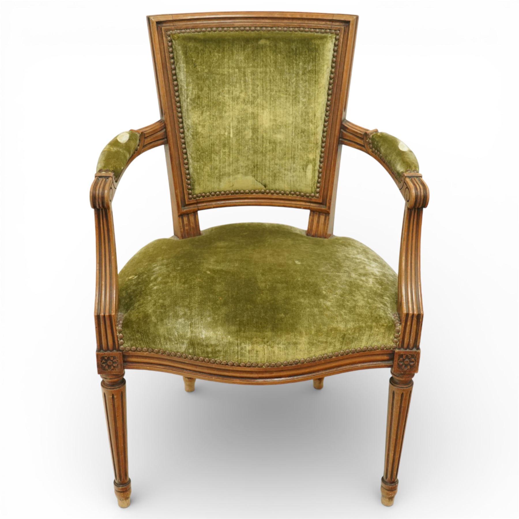 French Louis XVI style walnut armchairs, rectangular upholstered backs with nailhead trim, padded seats upholstered en suite, out-swept arms with upholstered pads, fluted supports with carved rosettes to the knees, on turned and fluted tapering legs
