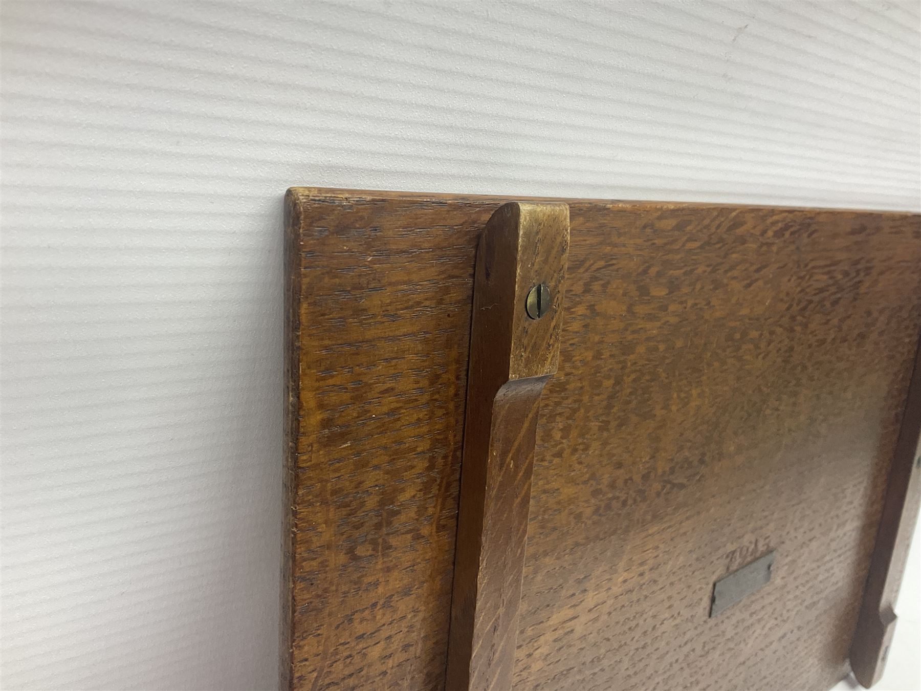 Arts and Crafts oak stand by Arthur Simpson of Kendal, of rectangular form with central hammered pewter panel, surrounded by a border with carved foliate corners, upon two bar supports, bearing label detailed 