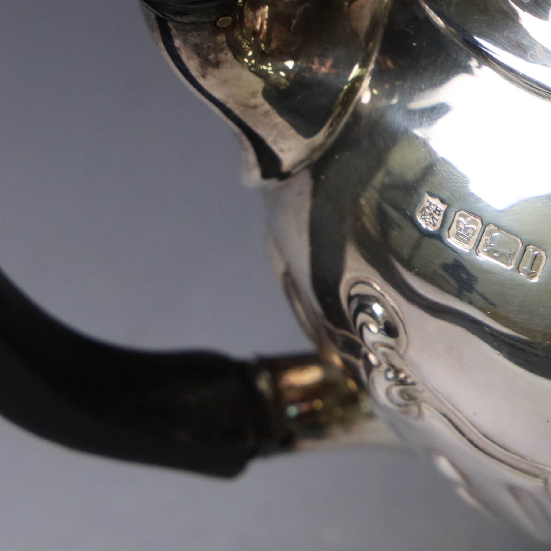 Edwardian silver three piece tea service, comprising teapot, twin handled open sucrier and a cream jug, each of oval form with embossed scrolling decoration and upon four bun feet, the teapot with ebonised wooden handle and finial, hallmarked Thomas Bradbury & Sons Ltd, Sheffield 1903, teapot H16cm