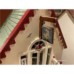 Seagull Pub - scratch-built wooden doll's house as a two-storey gable fronted public house painted in white green and maroon; the hinged front with ground floor veranda and window over opening to reveal two fully furnished rooms with dog-leg staircase and well stocked bar with bar-tender L31cm H62cm D37cm; together with Corner Shop and Dollies Pantry; a similarly painted scratch-built wooden two-storey flat-roofed doll's house as a well stocked ground floor grocery shop with stairs up to two further fully furnished rooms and more stairs giving access to a roof terrace L46cm H57cm D33cm (2)