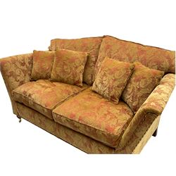 Duresta - two seat sofa, upholstered in red and gold patterned fabric decorated with scrolling foliage, on turned front feet with brass cups and castors