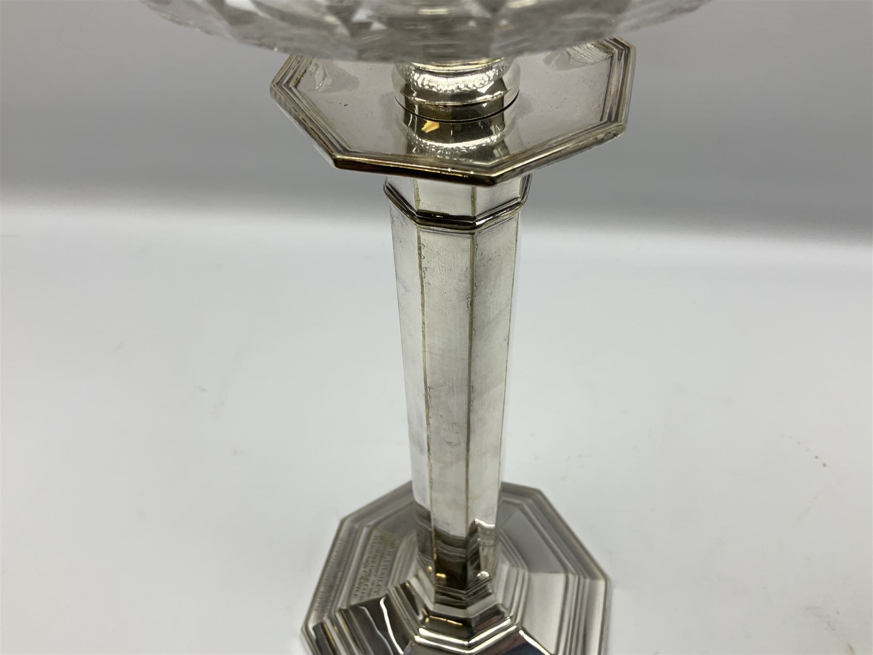 20th century Hawksworth, Eyre & Co silver plated oil lamp, the octagonal stepped base with engraved dedication, leading to an octagonal column supporting a faceted clear glass reservoir, Hinks Duplex burner, clear glass chimney, and cranberry glass shade, overall H71.5cm