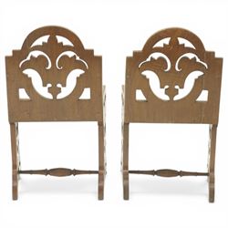 Gothic Revival oak ecclesiastical chairs, shaped cresting rails over pierced foliate splat backs, plank seats above shaped and pierced friezes, raised on shaped end supports united by turned stretchers, on small brass castors