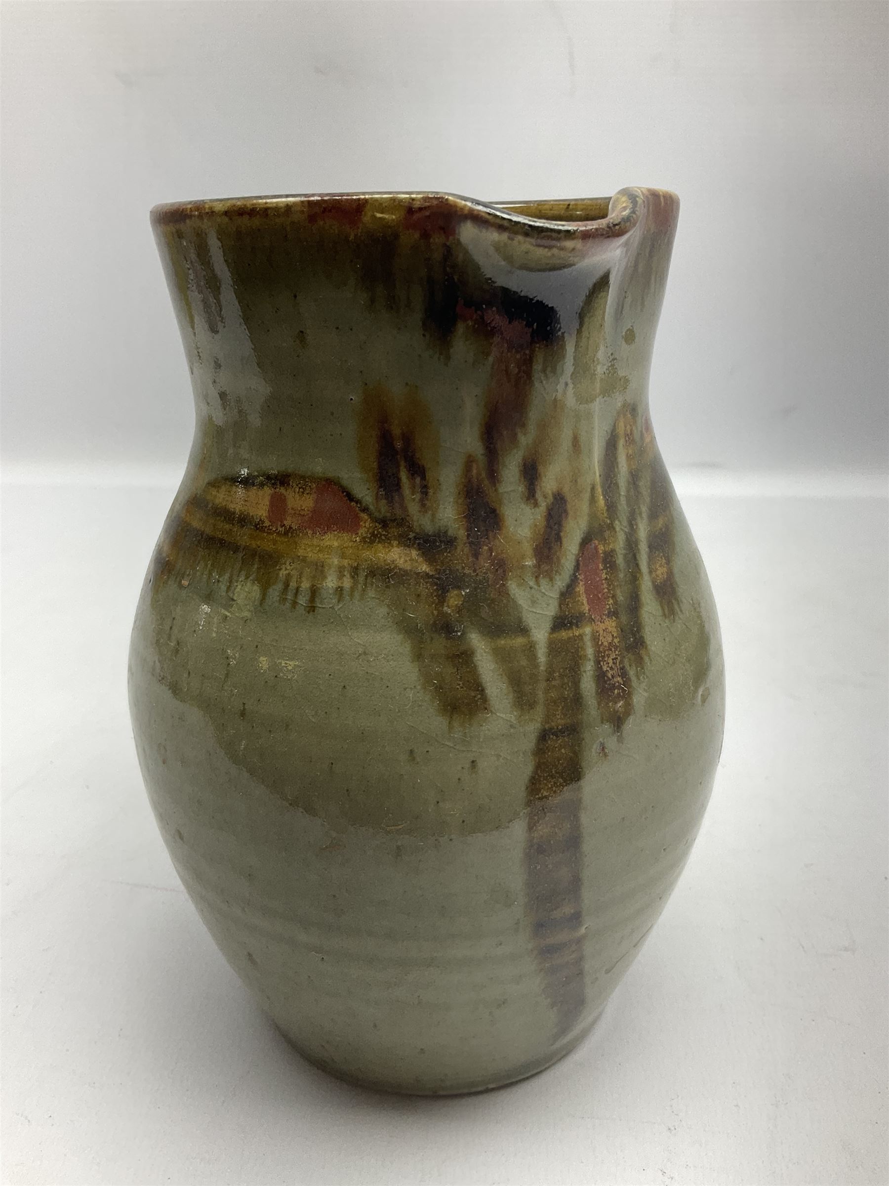 Michael Leach (British 1913-1985) for Yelland pottery; two large glazed stoneware plates with dark brown stylised decoration upon oatmeal ground, together with a jug in merging blue, green and brown, all with impressed marks beneath, largest plate D37cm