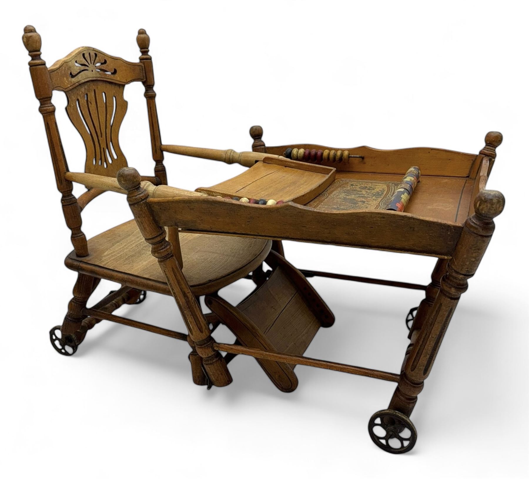 Late 19th century American oak child's metamorphic high chair and play table, carved spindle backrest with pierced splat, detachable tray with abacus and hand painted pastoral decoration, on turned supports with metal wheels