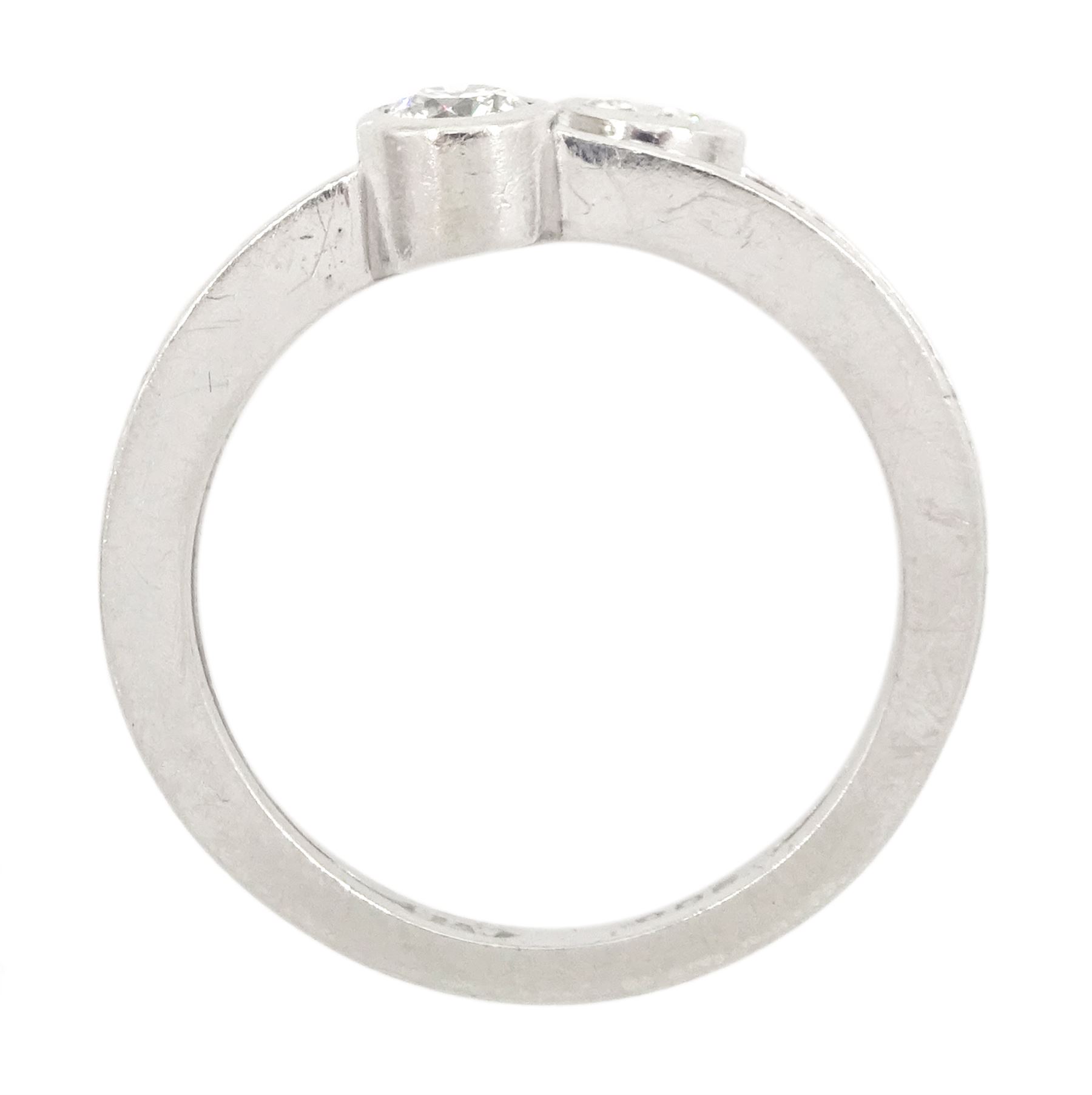 Platinum bezel set, two stone round brilliant cut diamond, crossover ring, London 1985, total diamond weight approx 0.50 carat